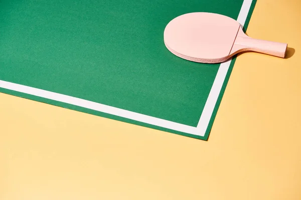 Raqueta de madera para tenis de mesa sobre fondo verde y amarillo - foto de stock