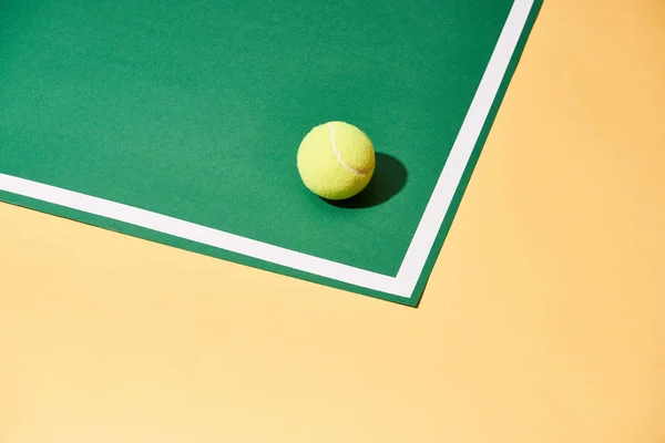Тенісний м'яч з тіні на зеленій і жовтій поверхні з білою лінією — стокове фото