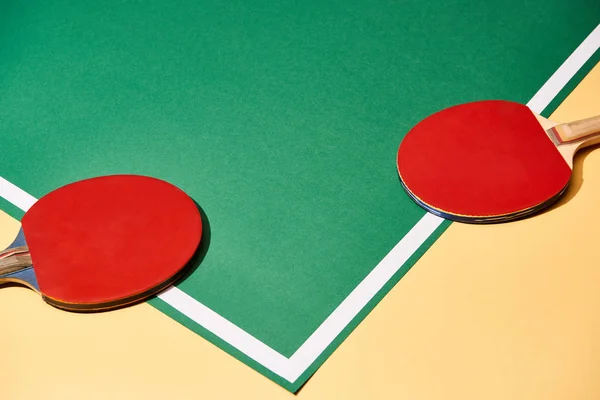 Две ракетки для пинг-понга на желтой и зеленой поверхности — стоковое фото