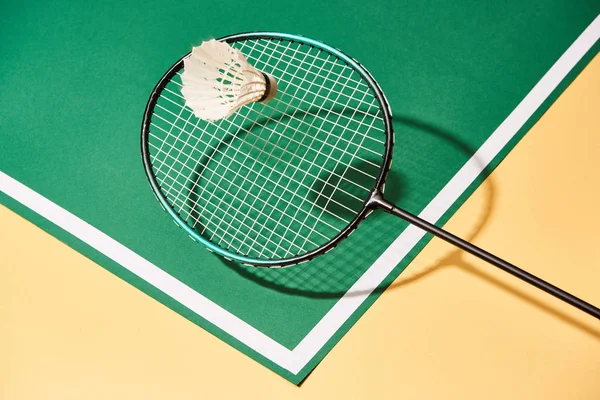 Raqueta de bádminton y lanzadera en superficie verde y amarilla con línea - foto de stock