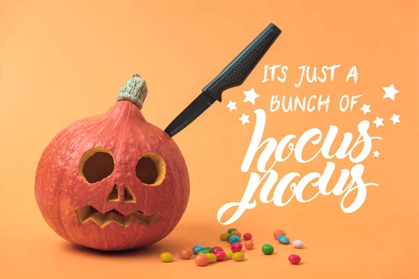 Gruseliger Halloween-Kürbis mit Messer und Bonbons auf orangefarbenem Hintergrund mit Hokuspokus-Illustration — Stockfoto