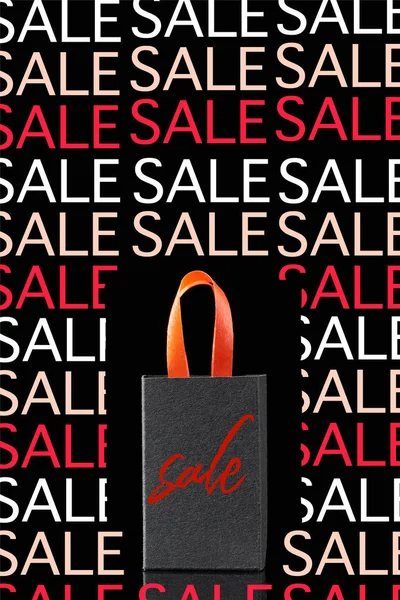 Paper shopping bag with red handle isolated on black with sale illustration — Stock Photo