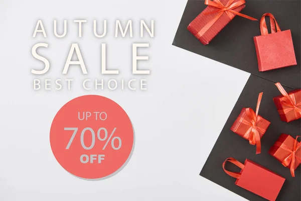 Vista superior de cajas de regalo rojas y bolsas de compras sobre fondo blanco y negro con hasta un 70 por ciento de descuento en la ilustración de venta de otoño - foto de stock