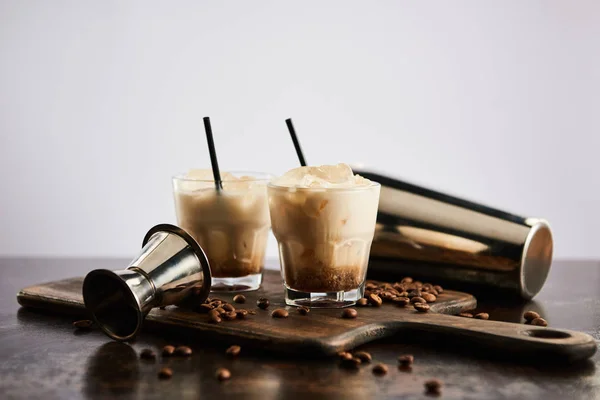 Cocktail russe blanc dans des verres avec pailles sur planche de bois avec grains de café isolés sur gris — Photo de stock