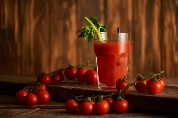 Selective focus of bloody mary cocktail in glass on wooden background with tomatoes — Stock Photo