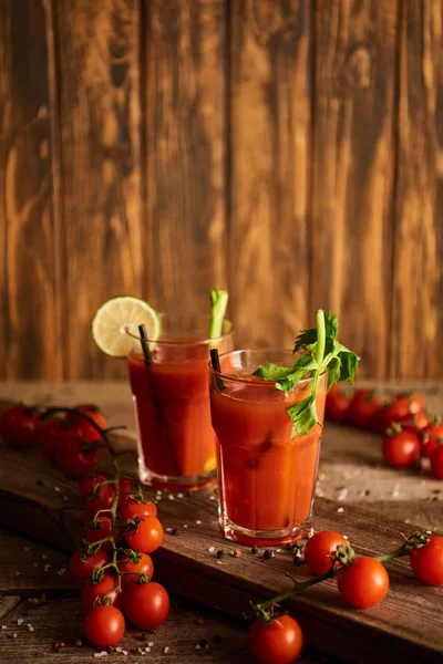 Foyer sélectif de cocktail Mary sanglante dans des verres sur fond de bois avec sel, poivre, tomates et céleri — Photo de stock
