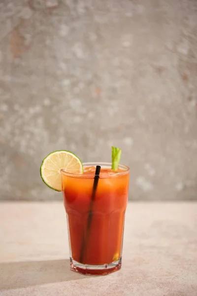 Blutiger Mary-Cocktail im Glas mit Limette, Sellerie und Stroh auf grauem Hintergrund — Stockfoto