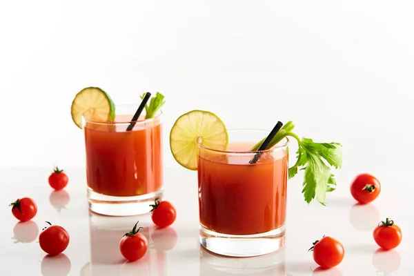 Cocktail à la marie sanglante dans des verres garnis de citron vert et céleri isolé sur blanc avec des tomates — Photo de stock