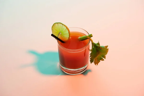 Blutiger Mary-Cocktail im Glas garniert mit Limette und Sellerie auf rot und blau beleuchtetem Hintergrund — Stockfoto