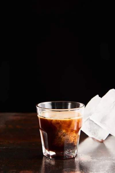 White russian cocktail in glass near ice cubes isolated on black — Stock Photo