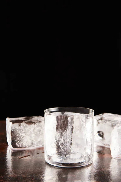 Vidro perto de cubos de gelo isolado em preto — Fotografia de Stock