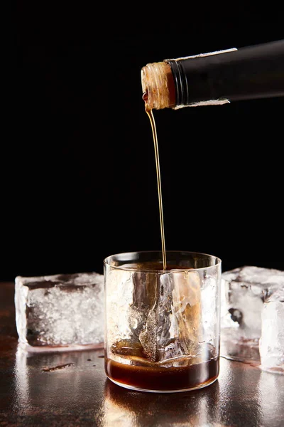 Kaffeelikör Porierung im Glas mit Eiswürfeln isoliert auf schwarz — Stockfoto