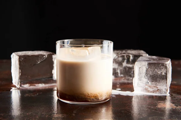 Белый русский коктейль в стакане возле кубиков льда, изолированных на черном — стоковое фото
