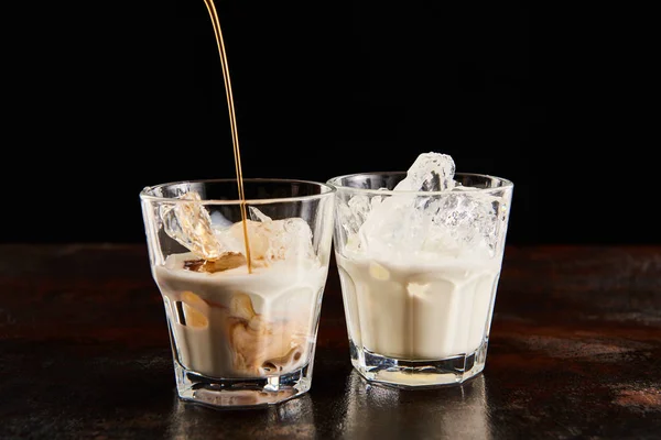 Liquore al caffè poring in bicchieri con cubetti di ghiaccio isolati su nero — Foto stock