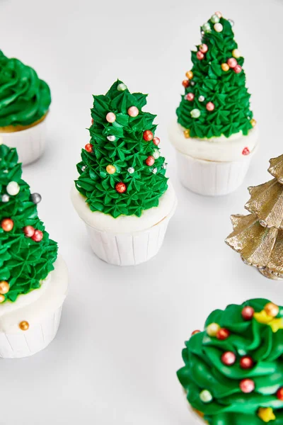 Leckere Cupcakes und dekorativer goldener Weihnachtsbaum auf weißer Oberfläche — Stockfoto