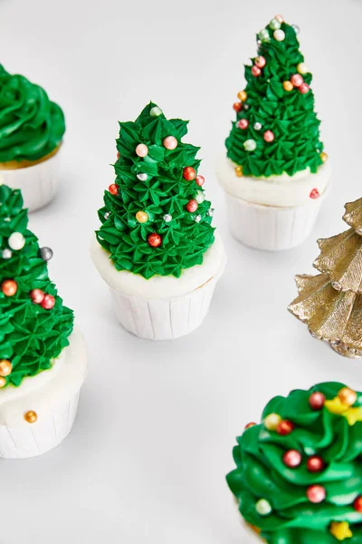 Delicious cupcakes and decorative golden Christmas tree on white surface — Stock Photo