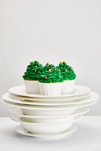 Sabrosos cupcakes de árbol de Navidad en platos blancos aislados en gris - foto de stock