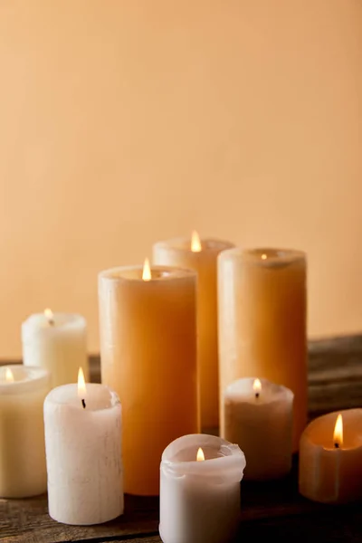 Nahaufnahme brennender Kerzen auf Holztisch auf beige — Stockfoto