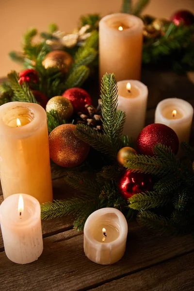 Burning candles with spruce wreath and christmas balls on wooden table — Stock Photo