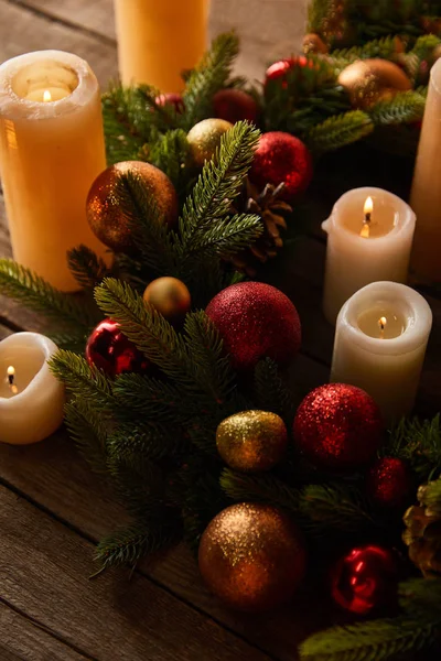 Brennende Kerzen mit Fichtenkranz und Weihnachtskugeln auf Holztisch — Stockfoto