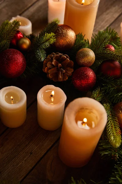 Close up of burning candles with spruce branches and christmas balls on wooden table — Stock Photo