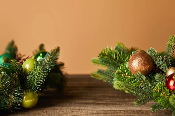 Decorative spruce branches with christmas balls on wooden table on beige — Stock Photo