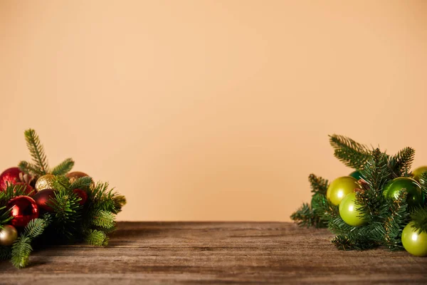 Spruce branches with christmas balls on wooden table on beige — Stock Photo