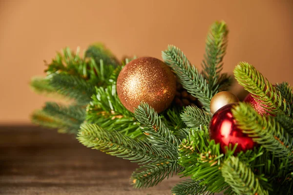 Festliche Fichtenzweige mit Weihnachtskugeln auf Holztisch auf beige — Stockfoto