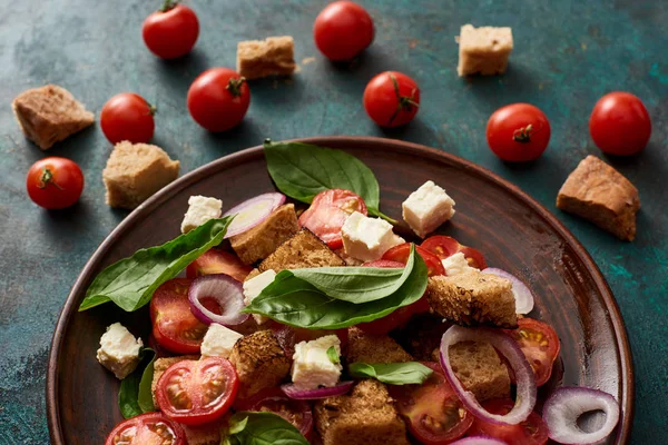 Свежий итальянский овощной салат panzanella подается на тарелке на столе с помидорами и гренками — стоковое фото