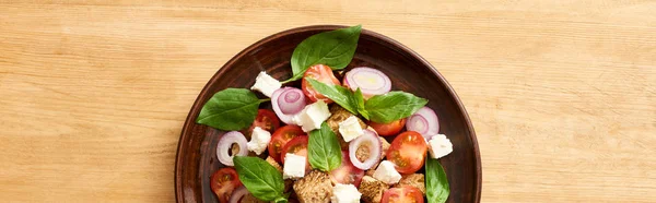 Blick von oben auf frisches italienisches Gemüsesalat Panzanella, serviert auf Teller auf Holztisch, Panoramaaufnahme — Stockfoto