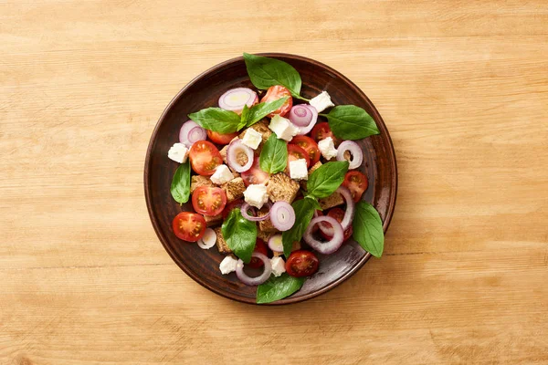 Vista dall'alto dell'insalata di verdure fresca italiana panzanella servita sul piatto sul tavolo di legno — Foto stock