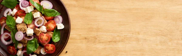 Top view of fresh Italian vegetable salad panzanella served on plate on wooden table, panoramic shot — Stock Photo