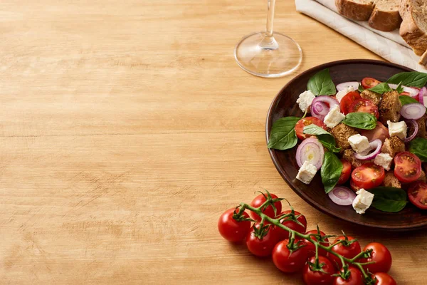 Deliciosa salada de legumes italiana panzanella servida em prato em mesa de madeira perto de tomates frescos, pão — Fotografia de Stock