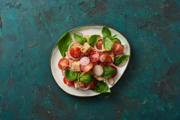 Vista superior da deliciosa salada de legumes italiana panzanella servida na placa na superfície verde texturizada — Fotografia de Stock