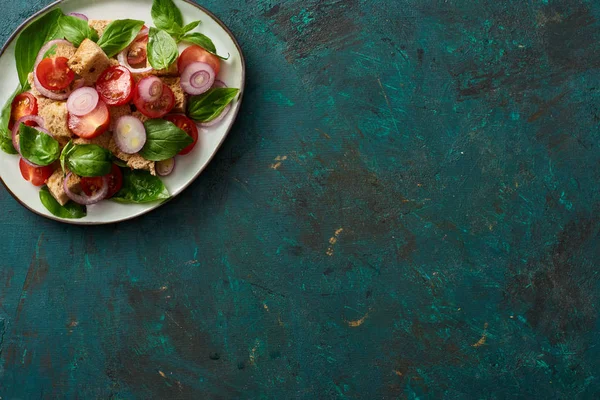 Vista superior de la deliciosa ensalada de verduras italiana panzanella servido en el plato en la superficie verde texturizada - foto de stock