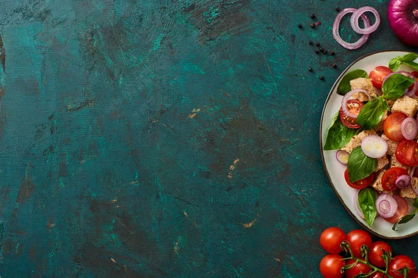 Vista superior de la deliciosa ensalada de verduras italiana panzanella servido en el plato en la superficie verde con textura con ingredientes - foto de stock