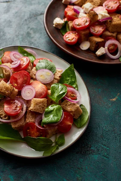 Delicious Italian vegetable salad panzanella served on plates on textured green surface — Stock Photo