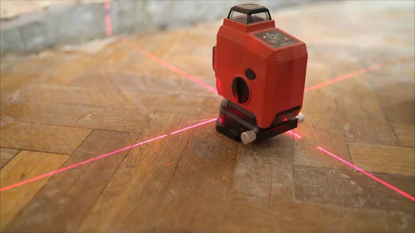 A laser level machine during measurement work in a dark setting. Setting the laser level. Apartment renovation