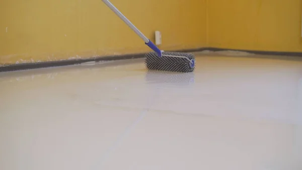 finishing work - a working roller primers the floor before pouring the floor. Workers poured into the bulk floor