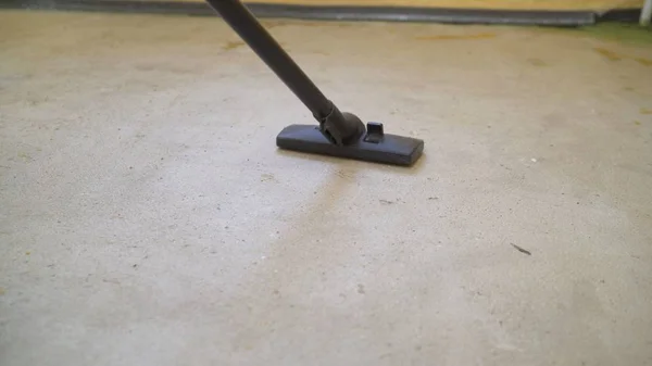 A worker using a vacuum cleaner removes construction debris. A worker is cleaning industrial premises. apartment after repair using polysos