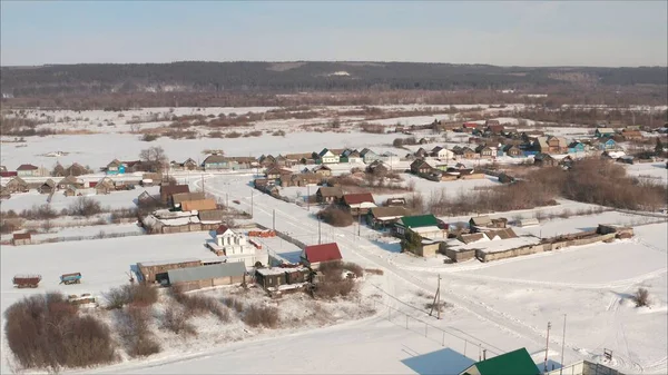 Russian village in winter shot from a quadrocopter. Aerial view of the typical Russian village covered with snow and countryside road. Shot. Winter in Russia, the periphery of Russia.