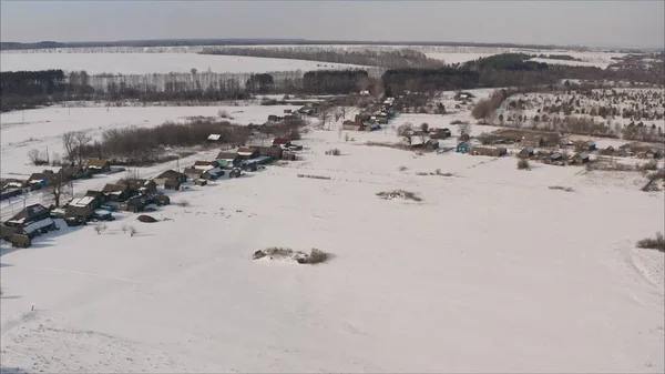 Russian village in winter shot from a quadrocopter. Aerial view of the typical Russian village covered with snow and countryside road. Shot. Winter in Russia, the periphery of Russia.