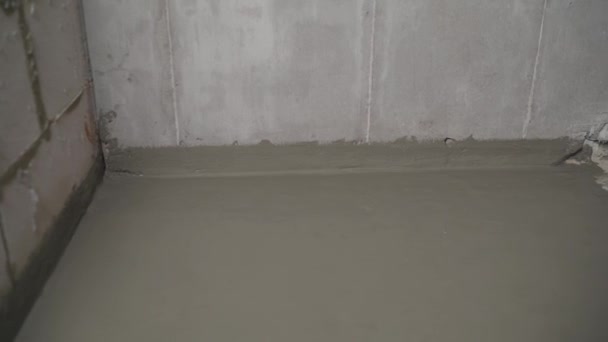 An industrial worker at a construction site installs a sealant for waterproofing cement. Worker puts liquid insulation on the floor. Workers applying the memory form of polymer waterproofing. Waterproofing concrete floor with mortar and brush.