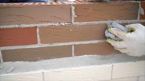 Brick house construction. Worker wipes the seams in the brickwork. Worker rewrites a brick wall.