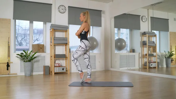 Girl trainer doing exercises at home. The girl is engaged in fitness at home. View from the side as a girl is engaged in fitness at home on the floor