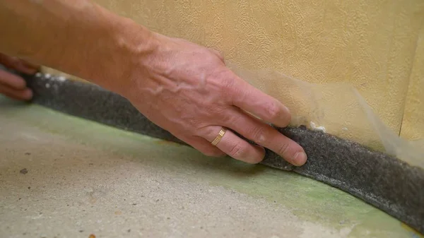 Glue the damper tape. Worker glues damper tape before laying the floor. Reinforcing tape for drywall. Damper tape for screed