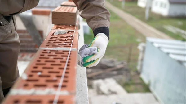 Brick house construction. Worker wipes the seams in the brickwork. Worker rewrites a brick wall.