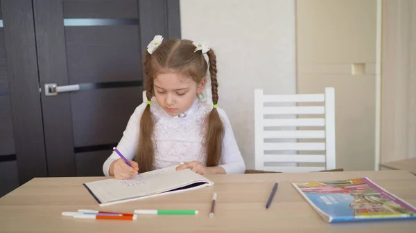 First-grader learns to draw at home. Little girl draws in an album.