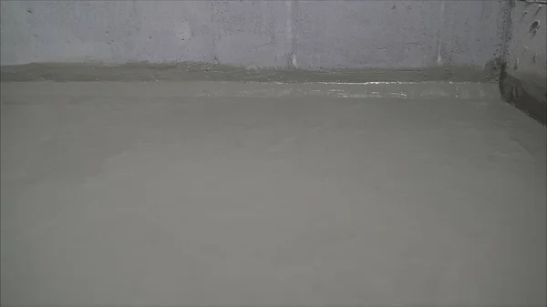 Concrete floor with fresh construction waterproofing. A worker is waterproofing a concrete floor. Construction mix waterproofing