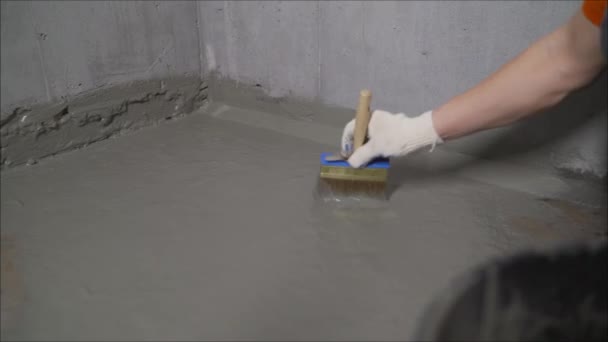 An industrial worker at a construction site installs a sealant for waterproofing cement. Worker puts liquid insulation on the floor. Workers applying the memory form of polymer waterproofing. Waterproofing concrete floor with mortar and brush. — Stock Footage Industrial Worker Construction Site Installs Sealant Waterproofing Cement Worker Puts Stock Video